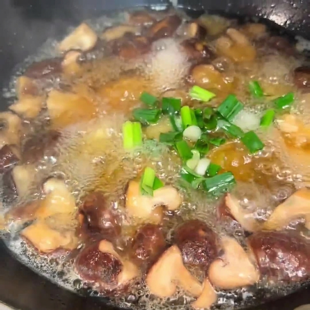 Cipollotti tritati che vengono sparsi in una pentola fumante di zuppa di funghi e tofu.