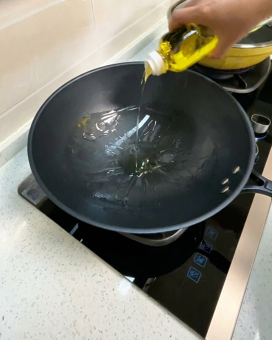 Olio da cucina versato in un wok nero preriscaldato.