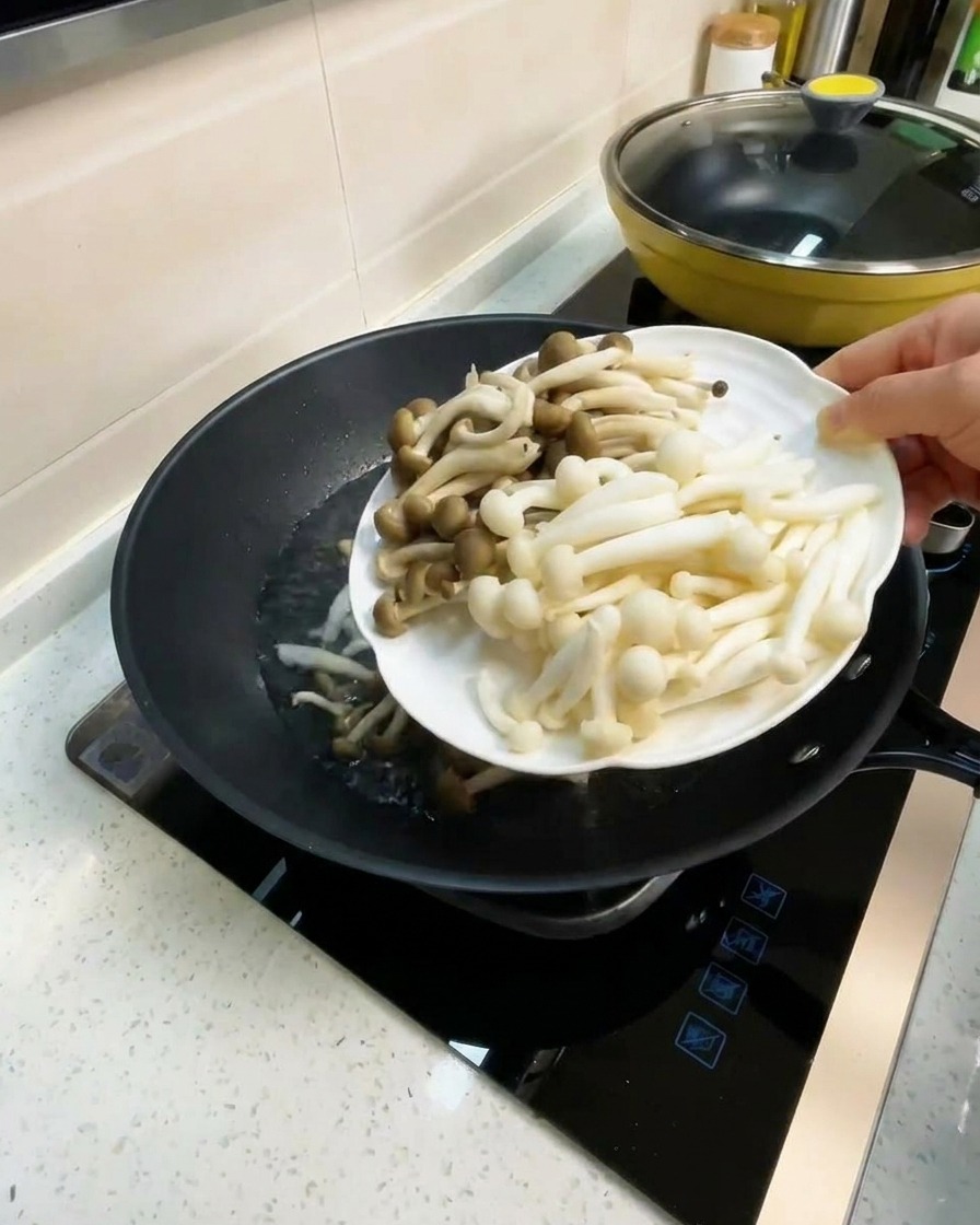 Un piatto di funghi pioppini bianchi e dal sapore di granchio aggiunti a un wok con brodo bollente.