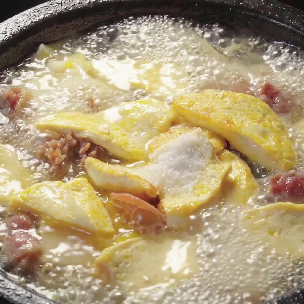 Condimenti mescolati in una pignatta in ebollizione di zuppa di funghi e tofu.
