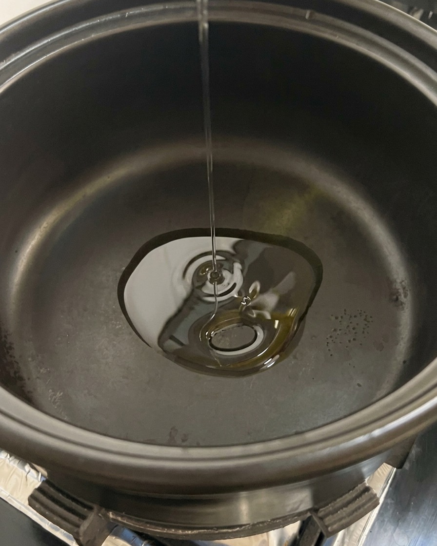 Funghi champignon bianchi affettati versati in una pentola nera contenente olio caldo.