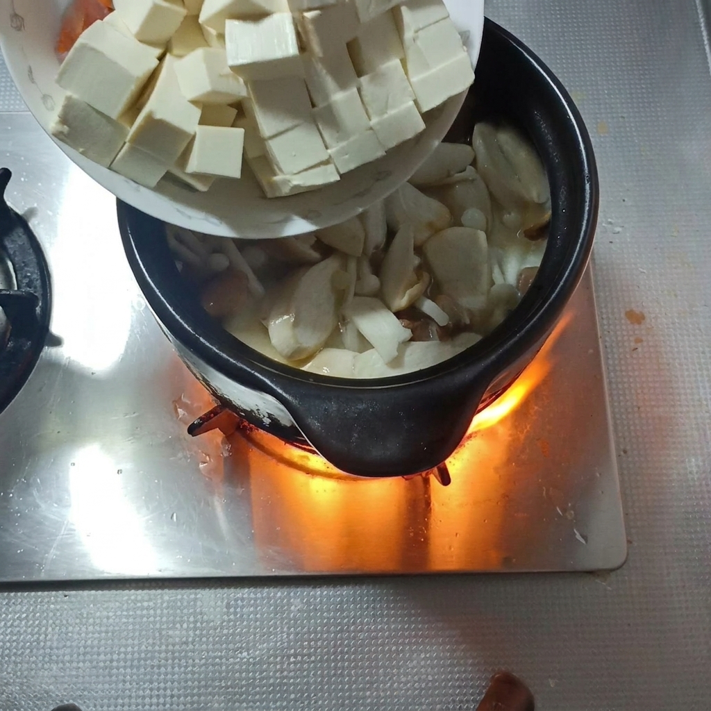 Cubetti di tofu morbido e fettine di carota aggiunti alla zuppa.