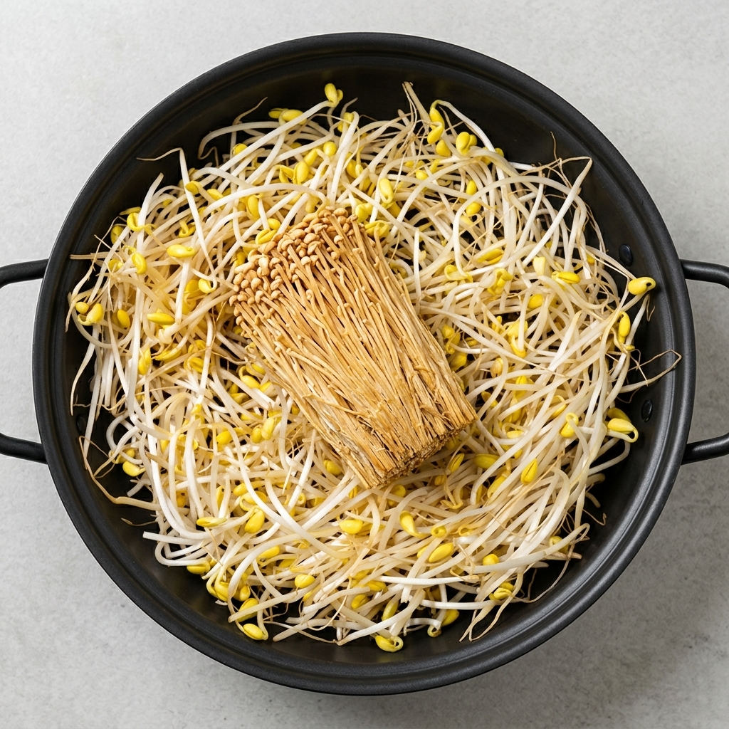 Una grande varietà di ingredienti pronti, tra cui germogli di soia, tofu, funghi enoki, spam e salsicce disposti ordinatamente in una pentola.