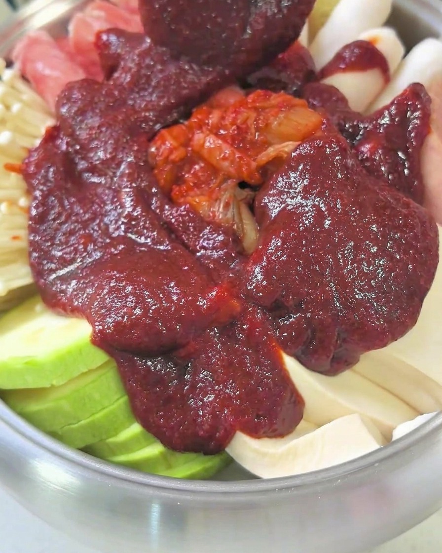 Una pentola piena di ingredienti e brodo, coperta da un coperchio, che sobbolle sui fornelli.