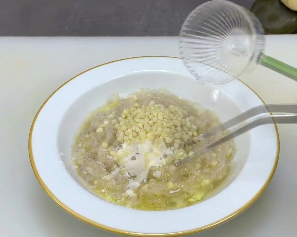 Pinzette di metallo mescolano piccoli semi di okra color crema in una densa pasta di gamberi.