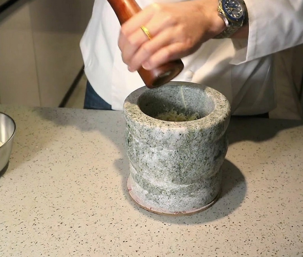 Un macinapepe in legno usato per macinare il pepe direttamente sopra gli ingredienti nel mortaio.