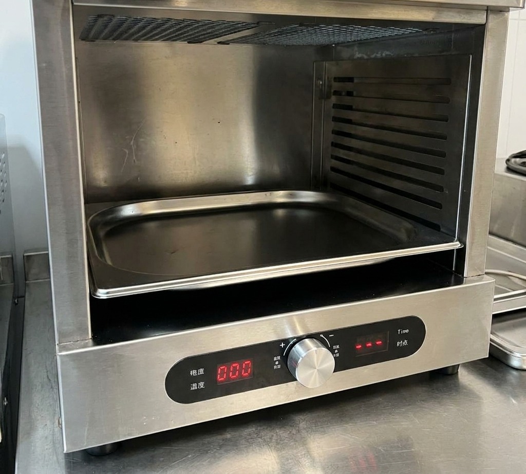 Primo piano di una mano che regola la manopola della temperatura su un forno professionale in acciaio inox.