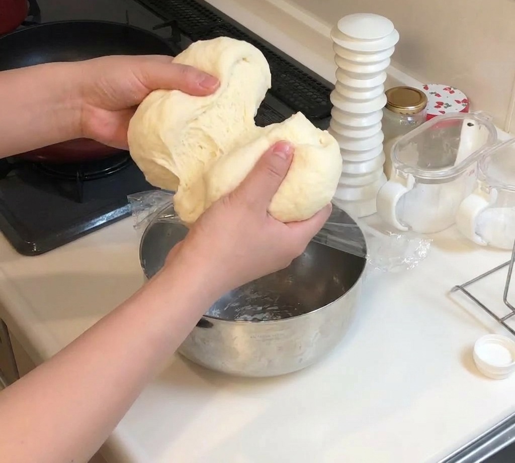Due mani dividono un grande pezzo di impasto morbido ed elastico in due sezioni uguali.