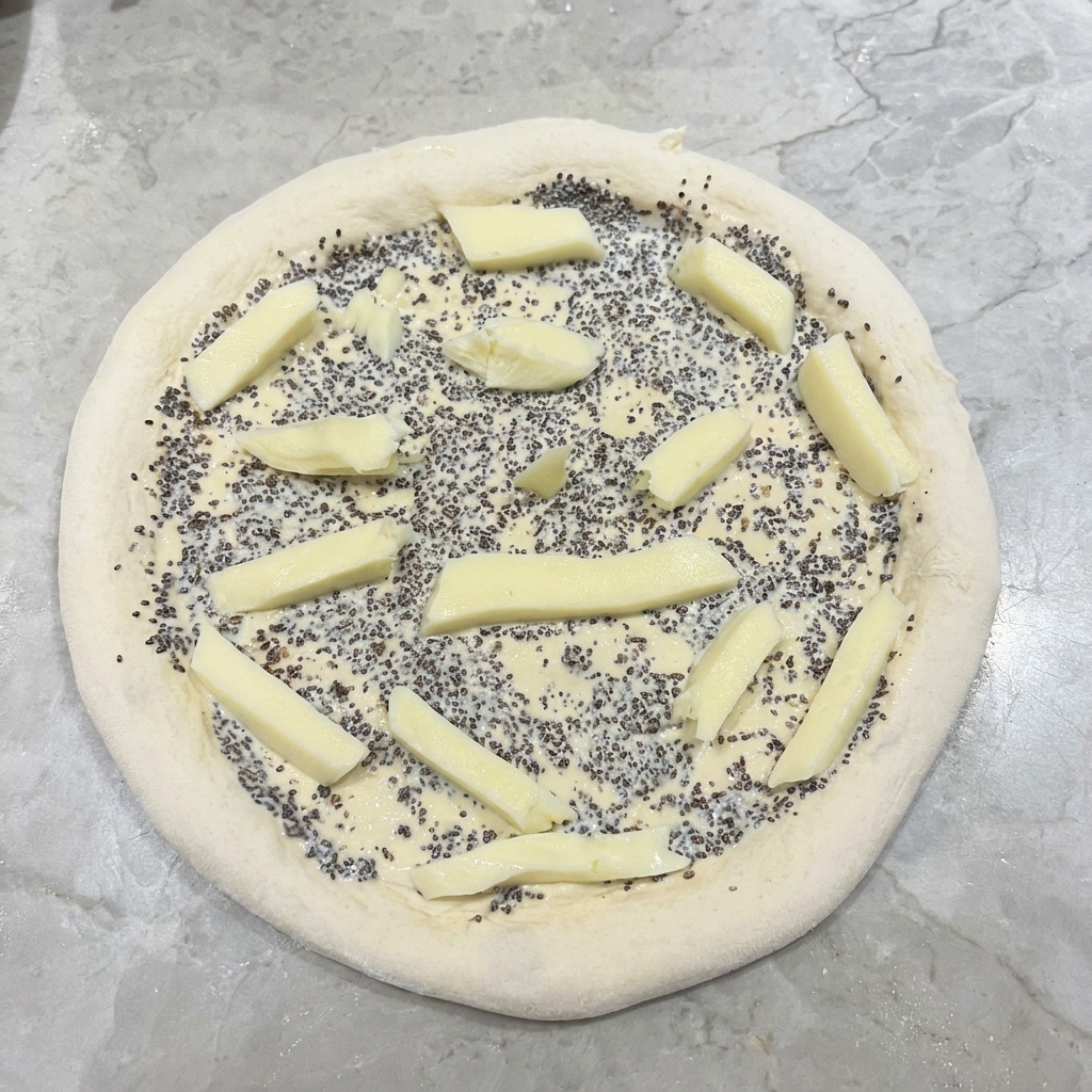 Bastoncini di mozzarella fresca disposti sopra la base della pizza coperta di salsa al tartufo.