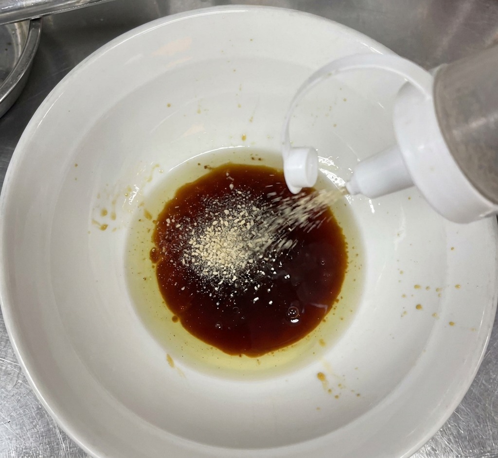 Sesamo bianco in polvere aggiunto alla base scura nella ciotola.