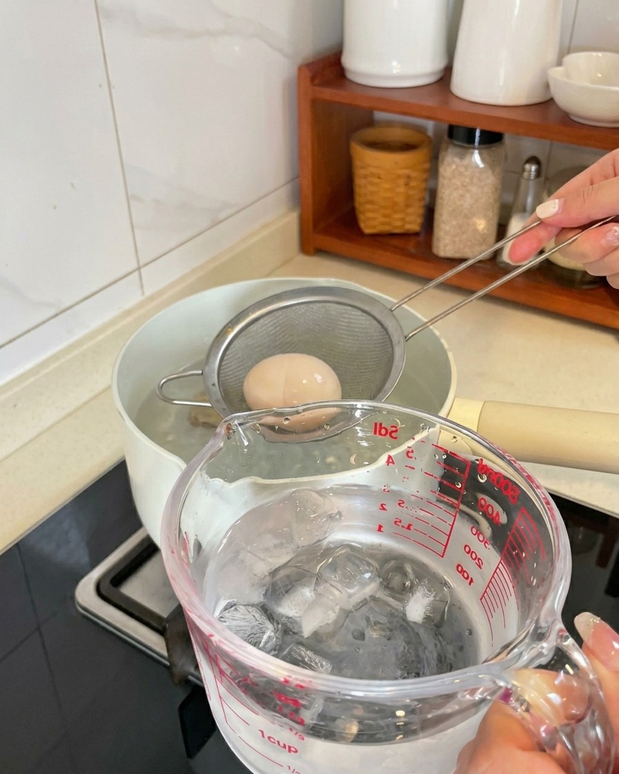 Un uovo sodo prelevato dalla pentola e messo in un contenitore con cubetti di ghiaccio e acqua.