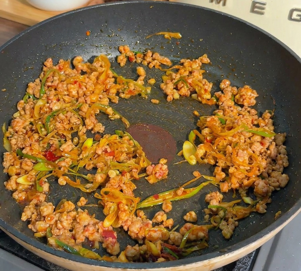 Carne di maiale macinata e cipollotti saltati in padella fino a doratura completa.