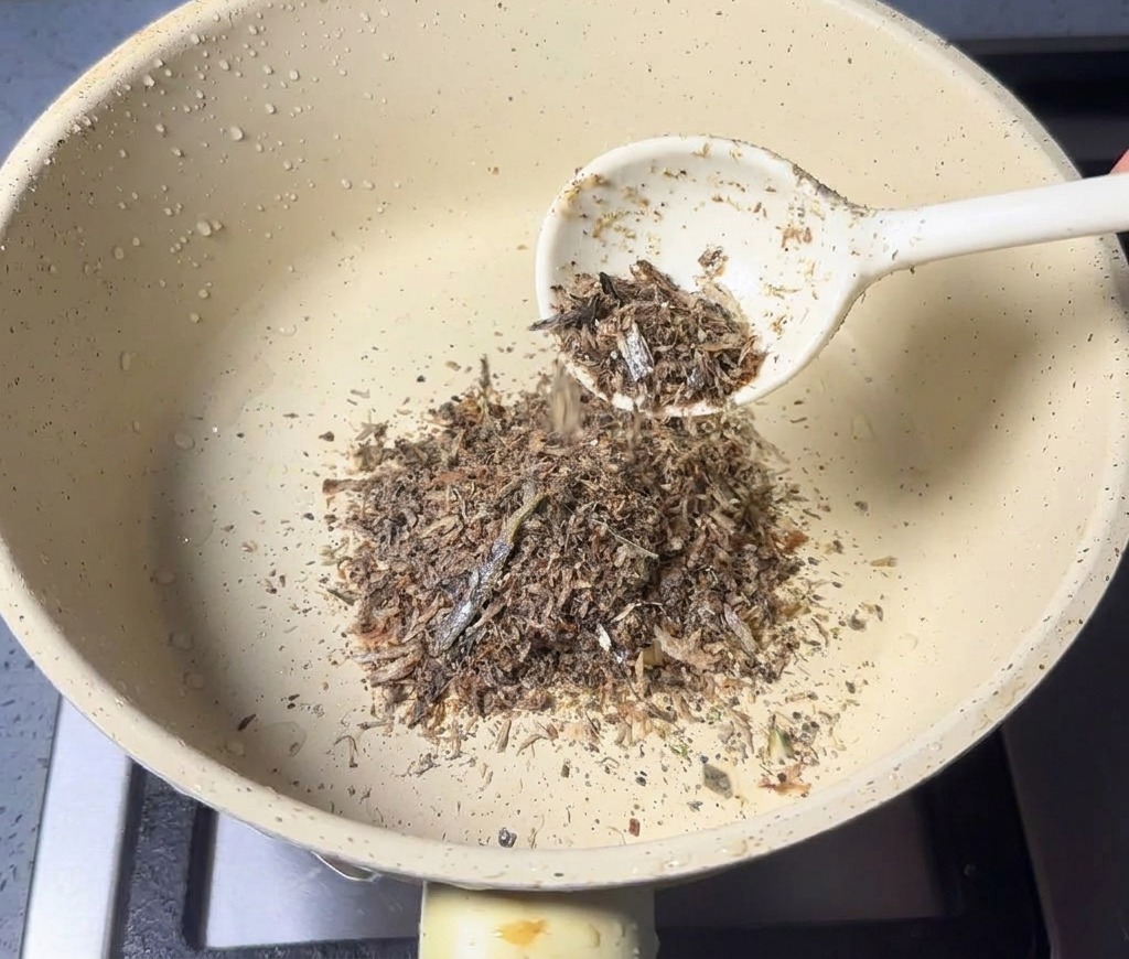 Un cucchiaio di polvere di mare aggiunta a un pentolino asciutto e di colore chiaro.