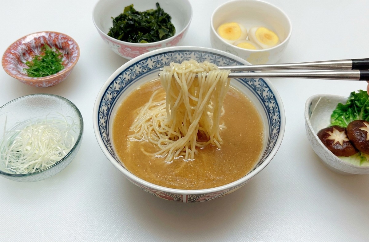 Bacchette dargento che sollevano e centrano i noodles allinterno della ciotola con brodo al miso.
