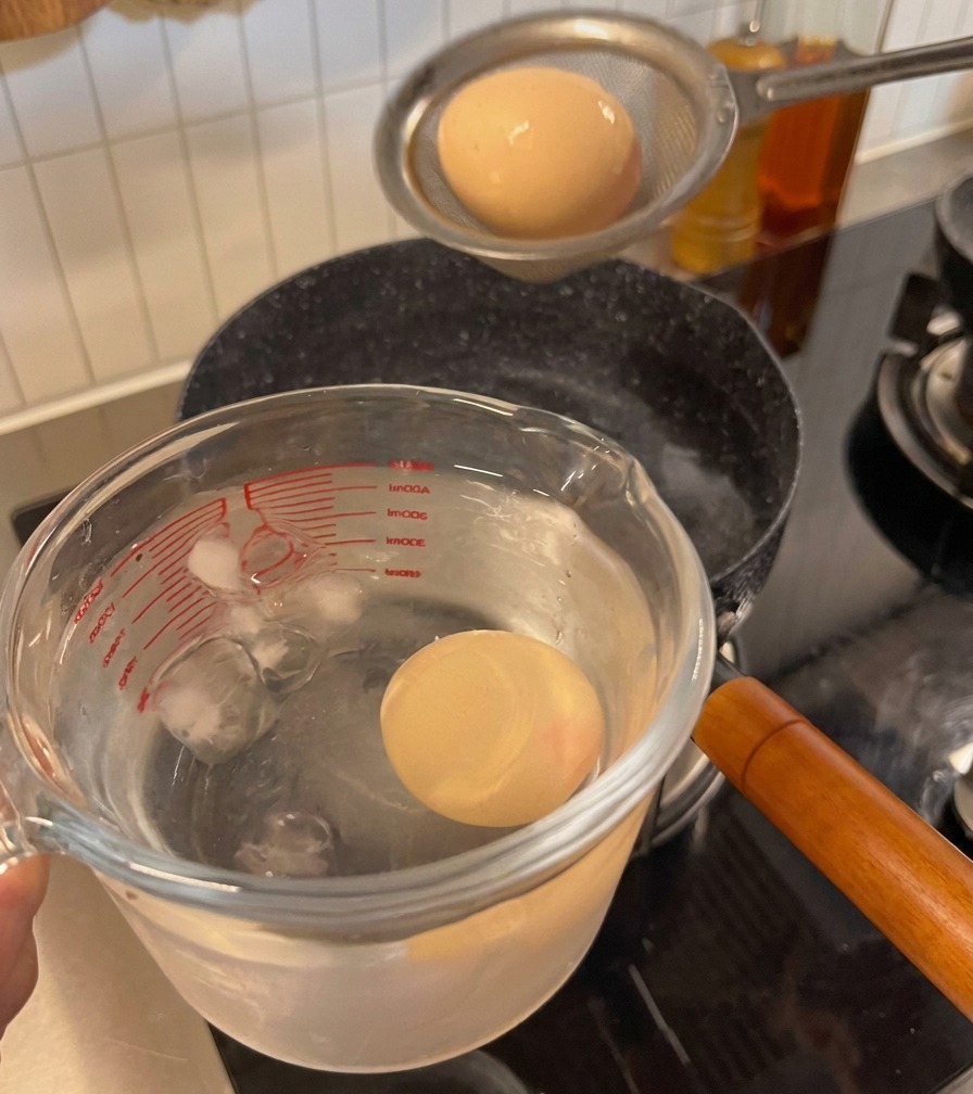 Uovo cotto trasferito dal colino a un contenitore con acqua e ghiaccio.