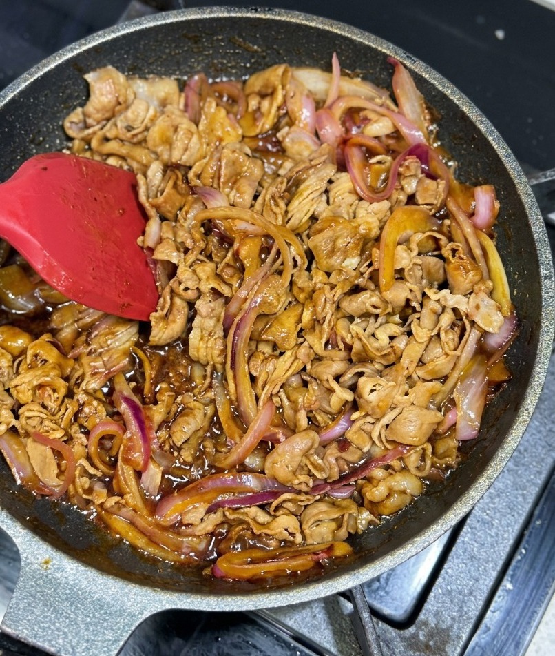 Manzo e cipolle saltati in padella avvolti da una glassa bruna e lucida.