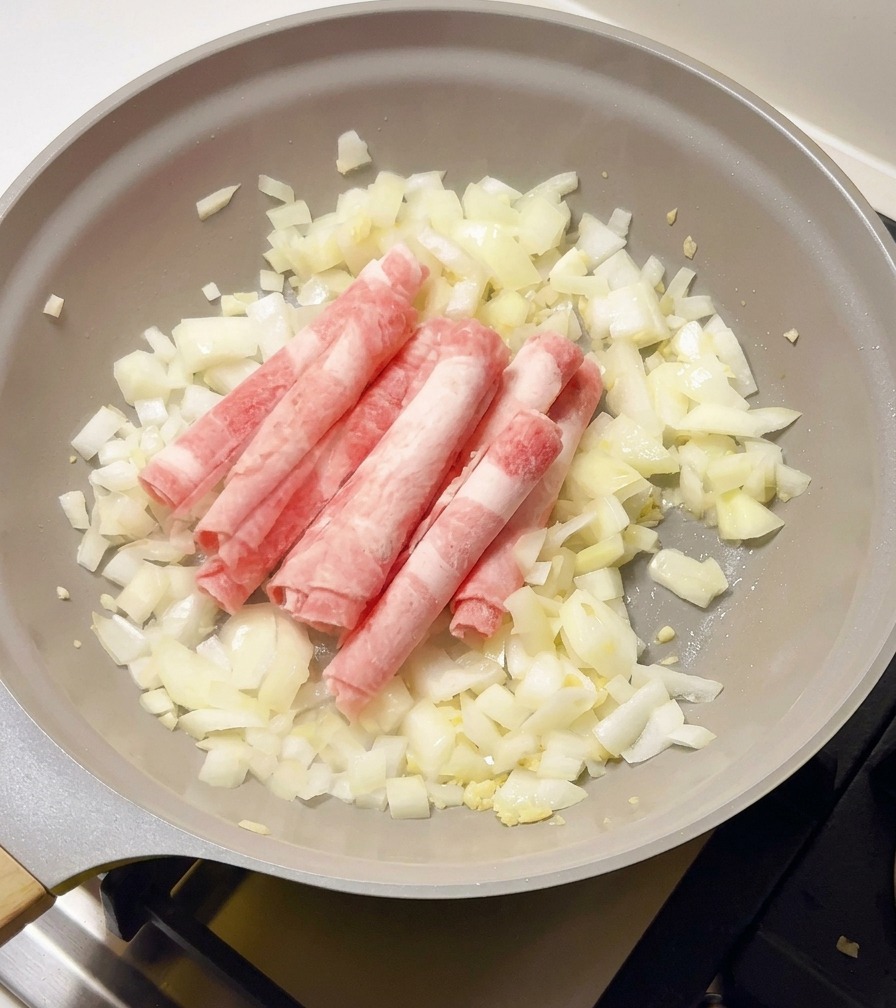 Fettine sottili di manzo crudo e congelato vengono aggiunte in padella sulle cipolle bianche saltate.