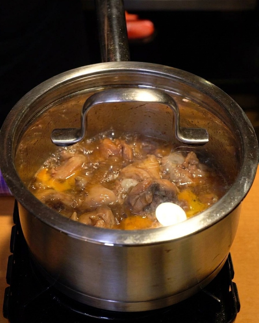 Un pentolino dacciaio con un coperchio di vetro trasparente sopra, con vapore e liquido bollente visibili attraverso il vetro.