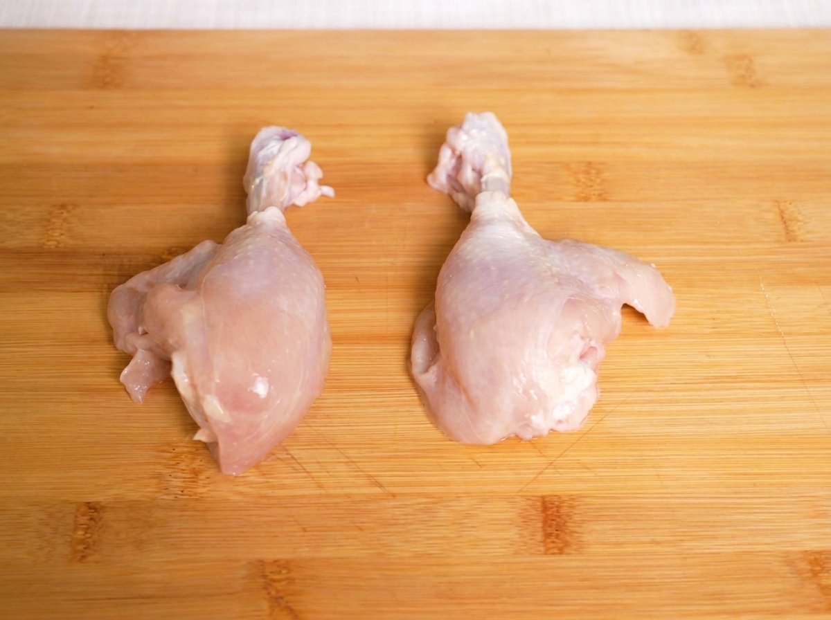 Sovracosce di pollo crudo su un tagliere di legno, pronte per essere affettate.