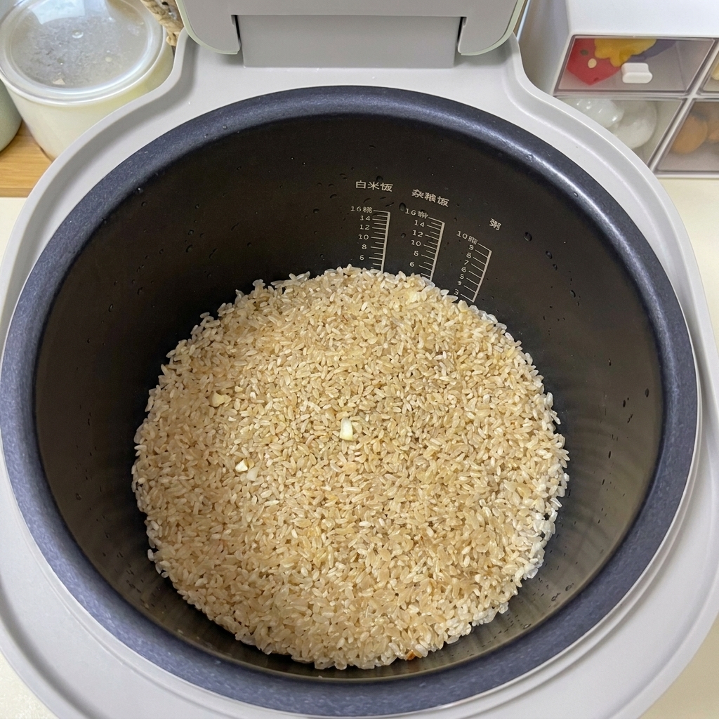 Riso condito di colore marrone chiaro appiattito uniformemente sul fondo di una pentola nera per cuociriso.