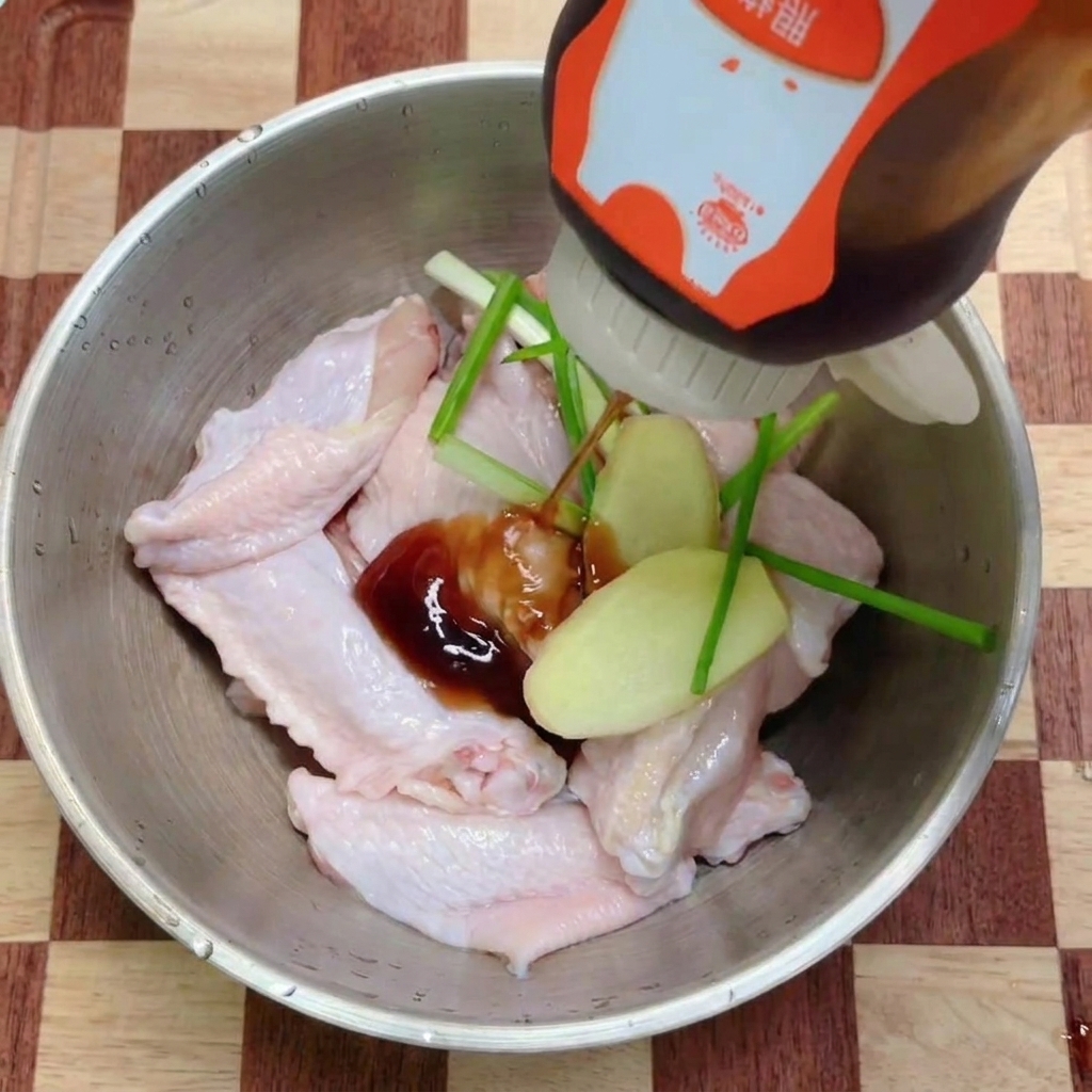 Salsa teriyaki versata sulle alette di pollo guarnite con aromi freschi.