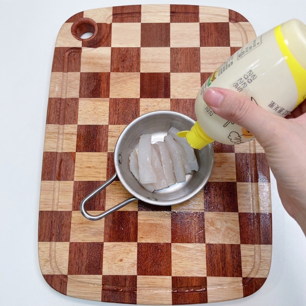 Mani che spremono succo di limone su strisce di merluzzo in un contenitore di metallo.