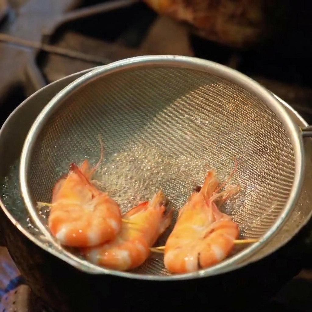 Tre gamberi interi immersi in un colino piatto allinterno di una pentola di acqua bollente.