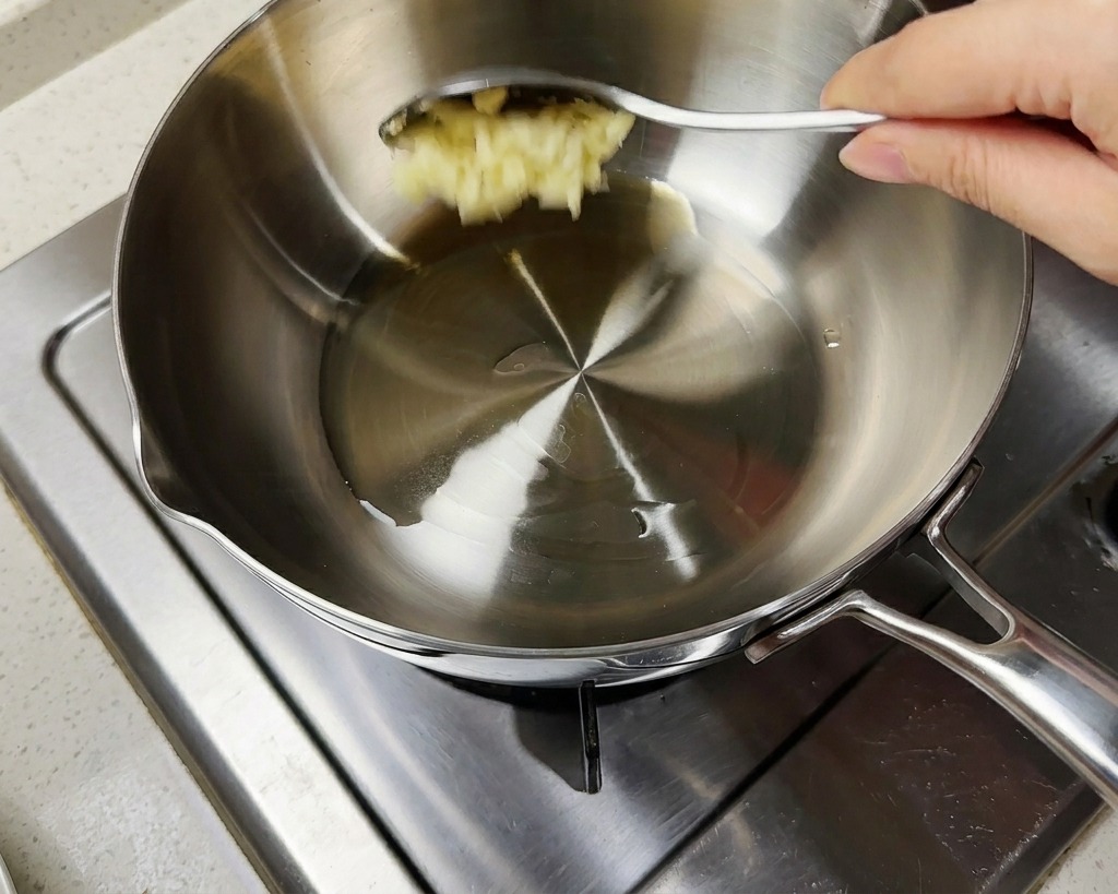 Aglio tritato e cipollotti aggiunti allolio caldo in una pentola.