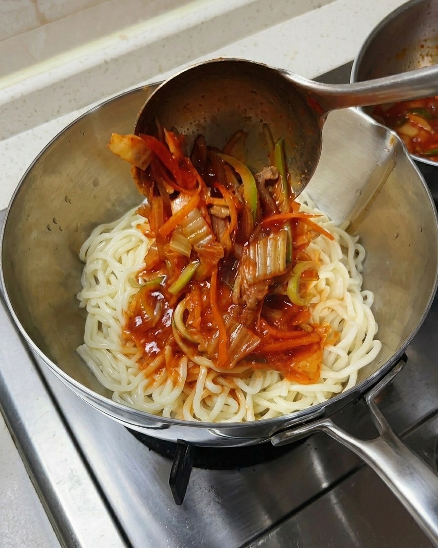 Mestolo che versa zuppa di mare e verdure su una ciotola di noodle bianchi spessi.