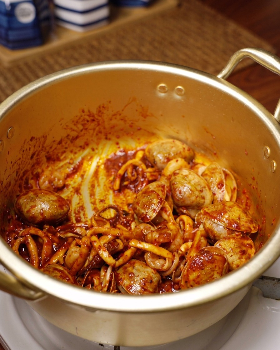 Calamari, gamberi e vongole ricoperti di peperoncino rosso saltati in una pentola dorata.