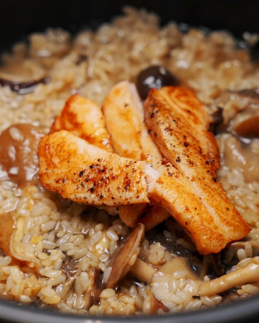 Tre pezzi di filetti di salmone dorati adagiati sopra riso crudo e funghi in un cuociriso.