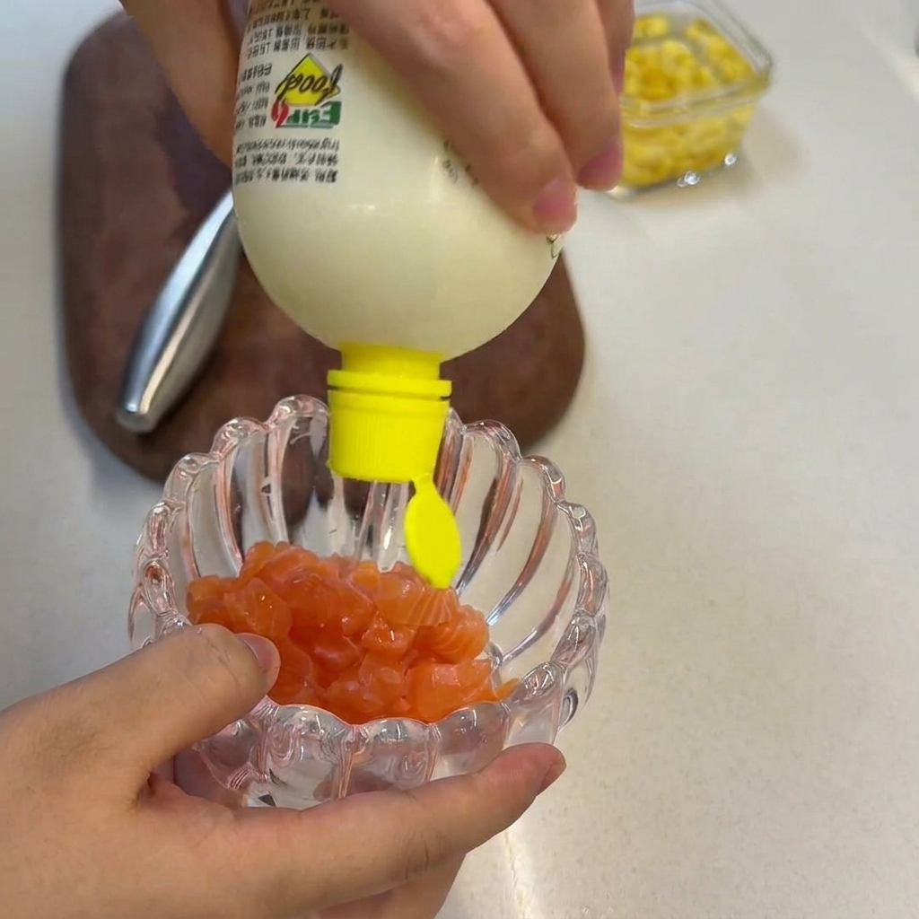 Succo di limone fresco spremuto da un flacone su una manciata di cubetti di salmone crudo allinterno di una ciotola di vetro.