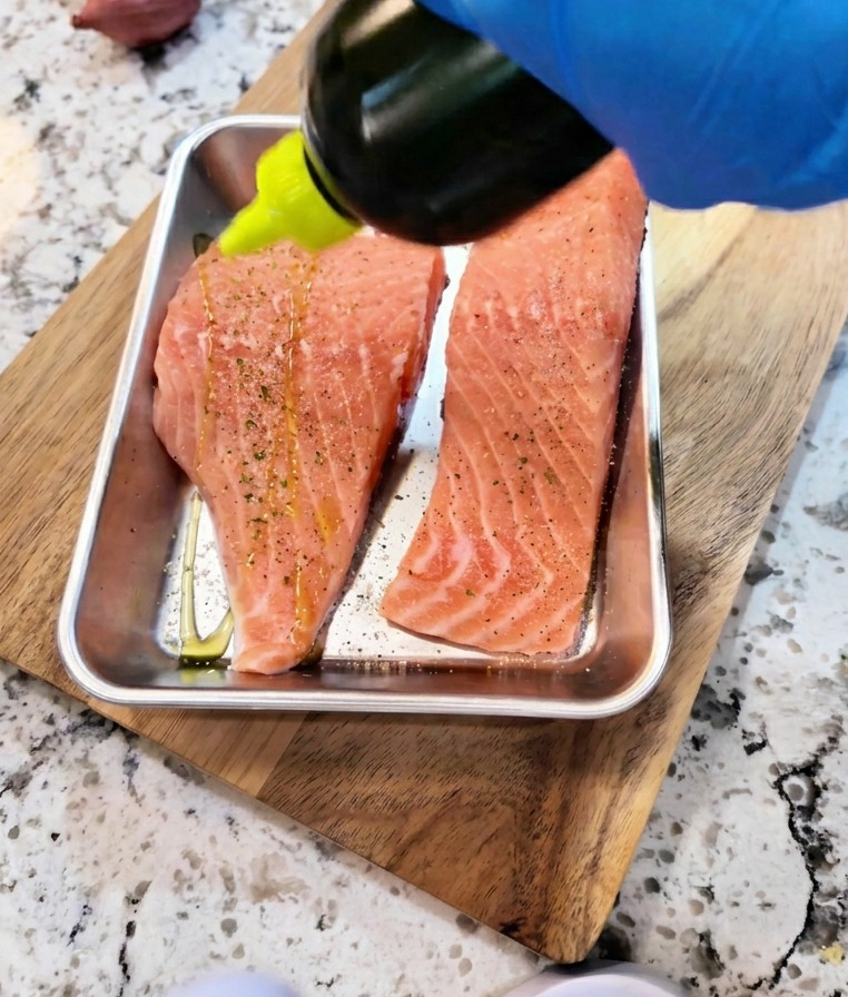 Salsa di soia e olio versati a filo sui filetti di salmone crudo per la marinatura.