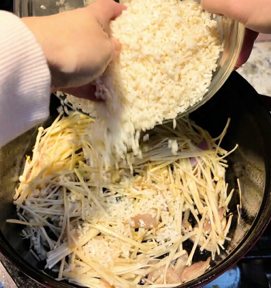 Due tazze di riso bianco vengono versate da una ciotola in una pentola contenente i funghi.