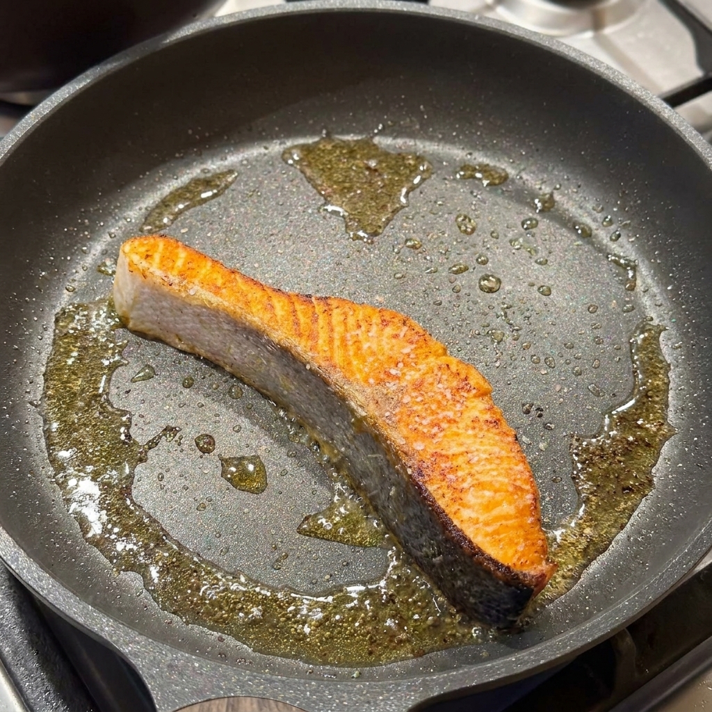 Un filetto di salmone scottato in padella condito con sale e pepe nero.
