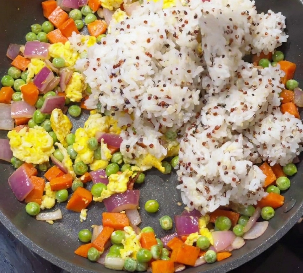 Riso bianco cotto e quinoa aggiunti in padella con verdure e uova.