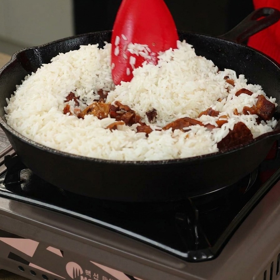 Riso e funghi mescolati con una spatola rossa in una padella di ghisa.