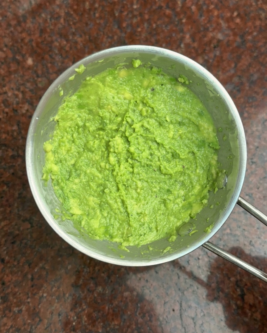Vista dallalto di una ciotola di metallo riempita con una pasta di avocado verde brillante.
