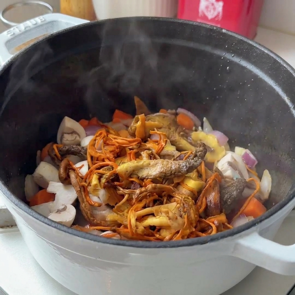 Varietà di funghi freschi e secchi aggiunti a una pentola fumante con verdure soffritte.