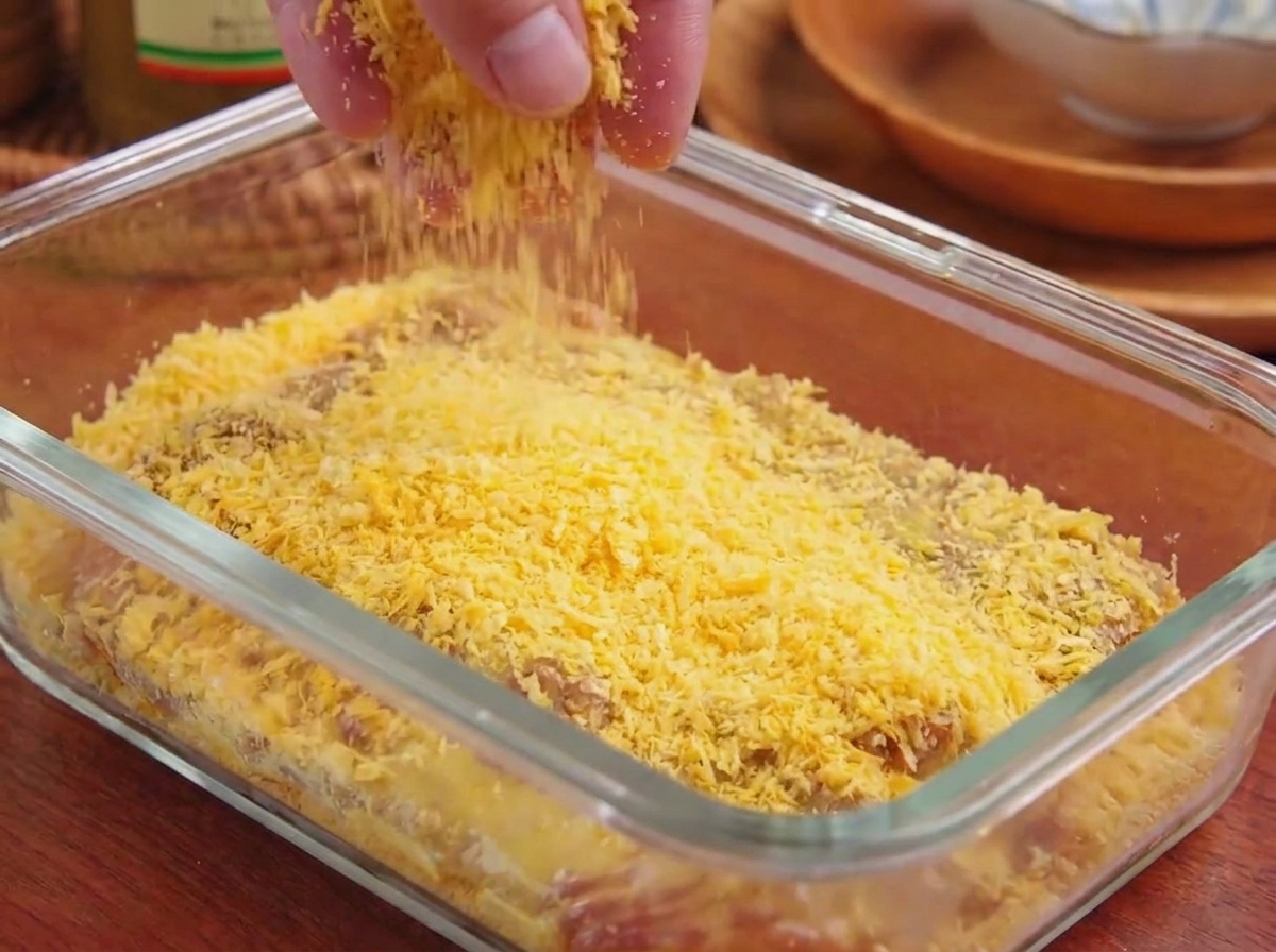 Pangrattato panko giallo cosparso e premuto sulla superficie di una cotoletta di maiale in una pirofila.
