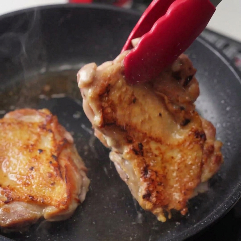 Pinze che sollevano il pollo mostrando il lato inferiore ben dorato e croccante con vapore che sale.