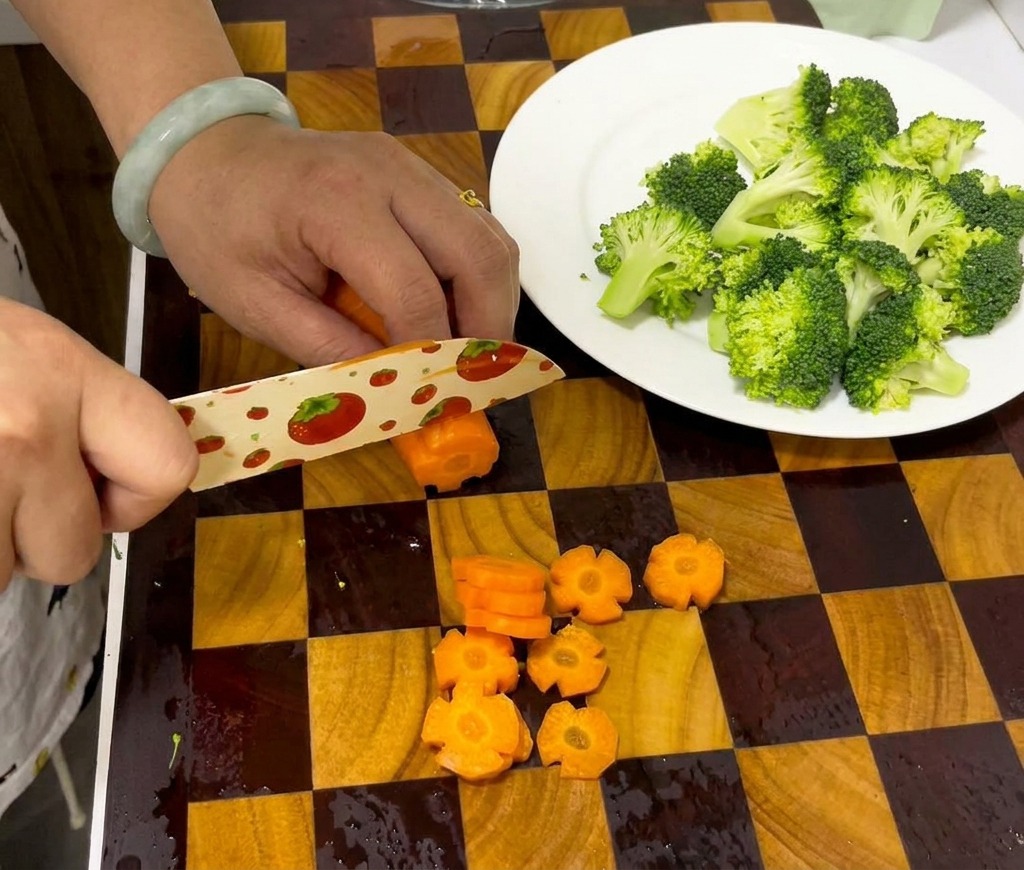 Mani che usano un coltello per affettare una carota incisa in dischetti decorativi a forma di fiore.