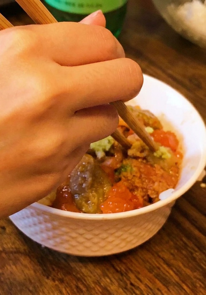 Una mano che usa le bacchette per posizionare una piccola quantità di wasabi al centro della ciotola.