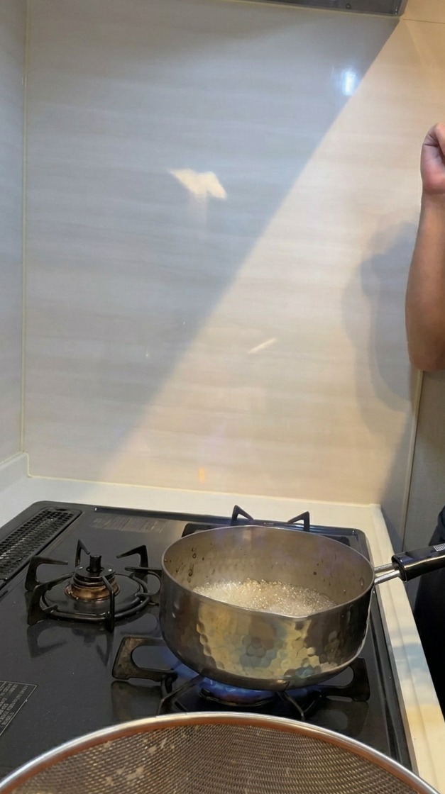 Una fiamma blu e arancione che divampa da un pentolino di metallo su un fornello a gas durante il processo di flambé.