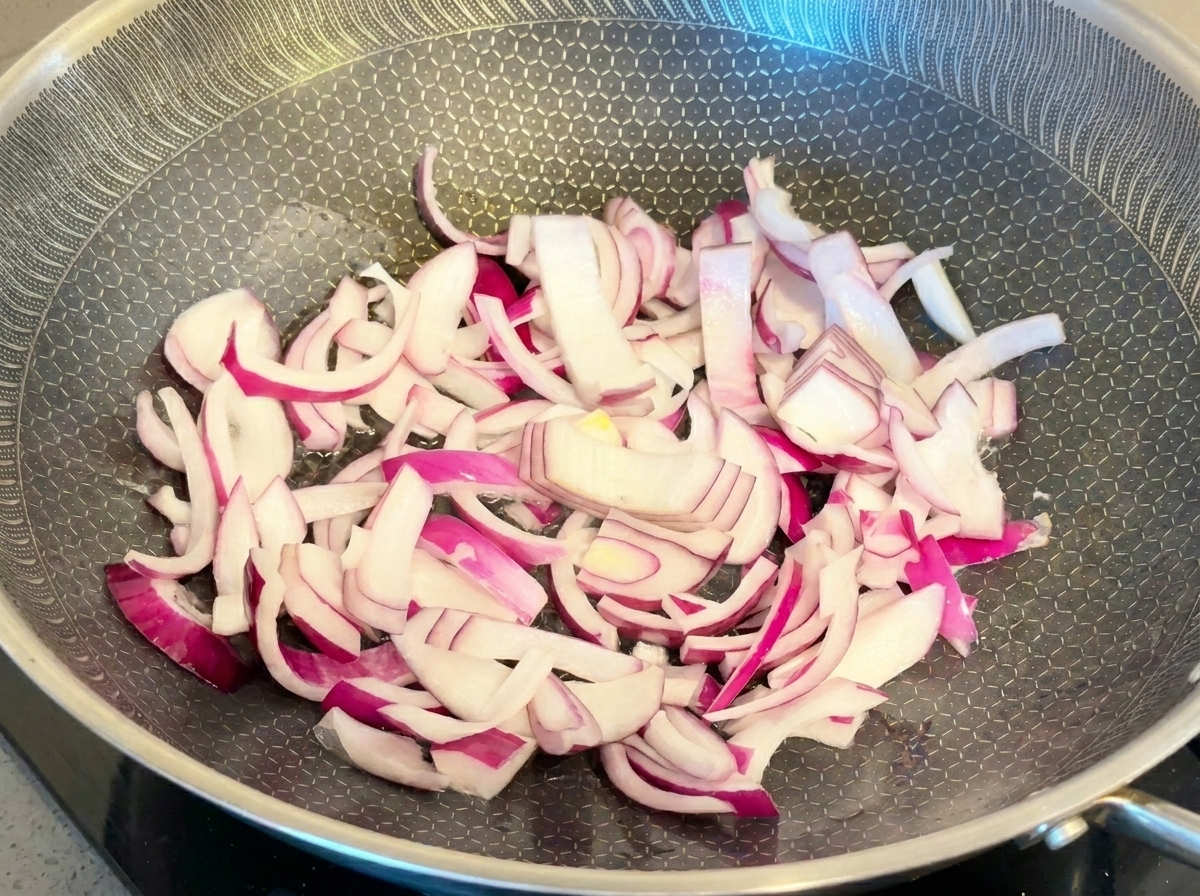 Fette di cipolla rossa saltate in una padella di metallo.