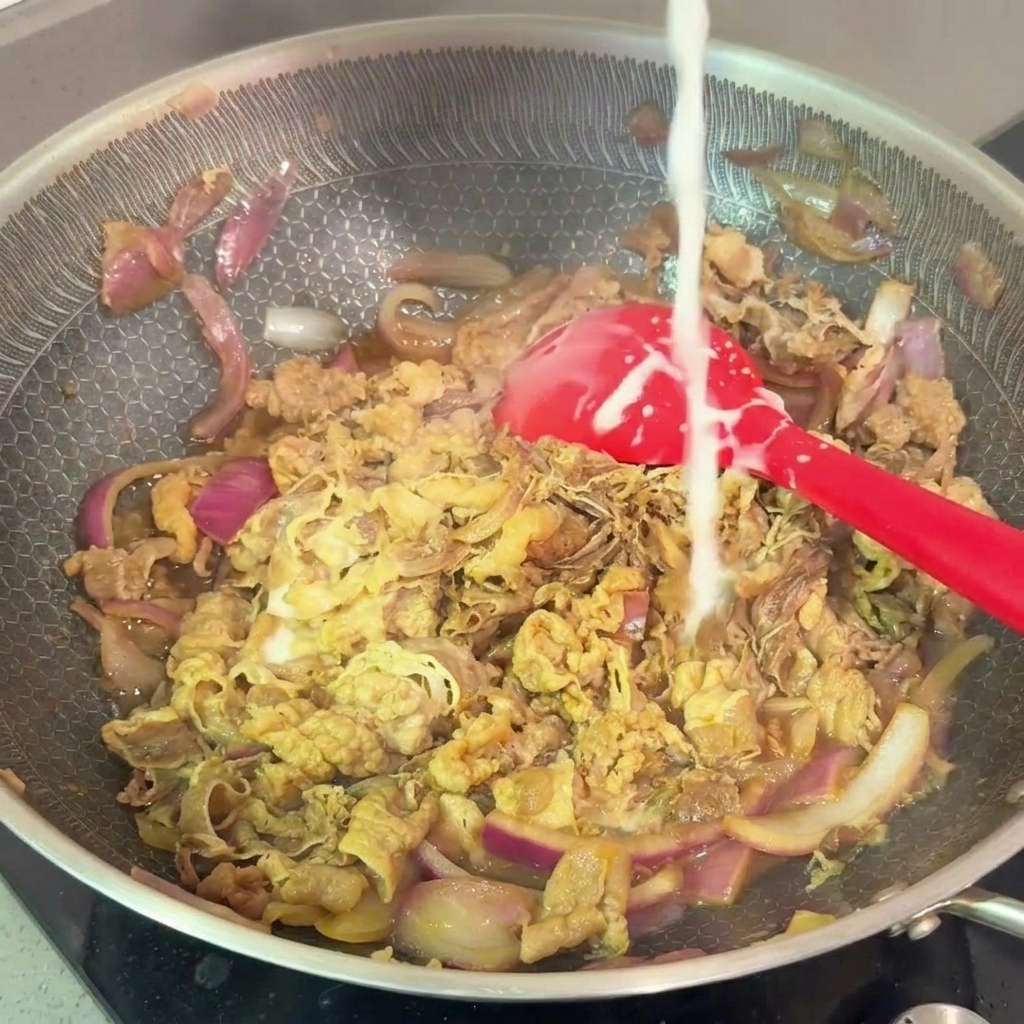 Un filo di acqua e amido versato nella padella con manzo e cipolle che sobbollono.