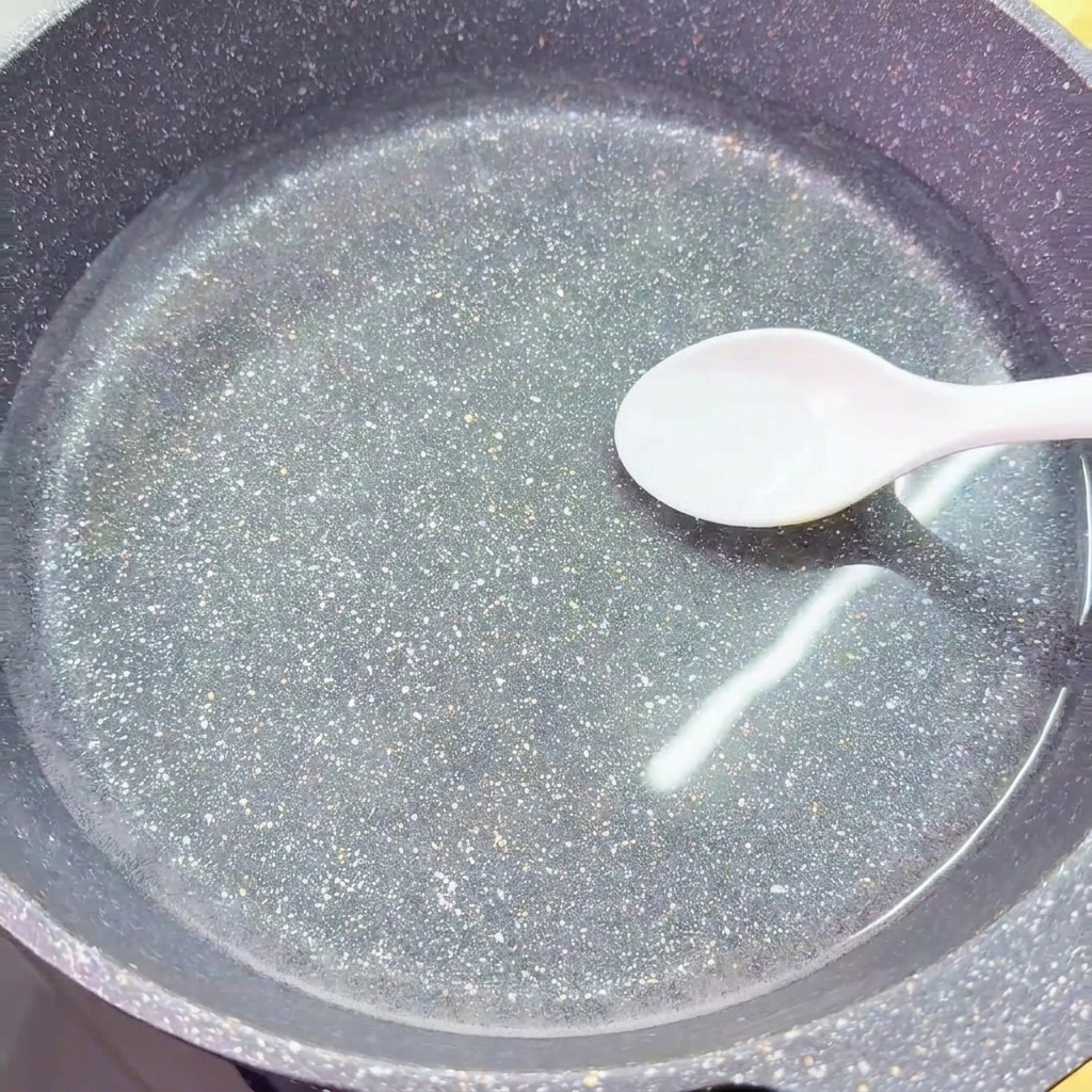 Un cucchiaio bianco aggiunge il sale in un wok pieno di acqua fredda e limpida.