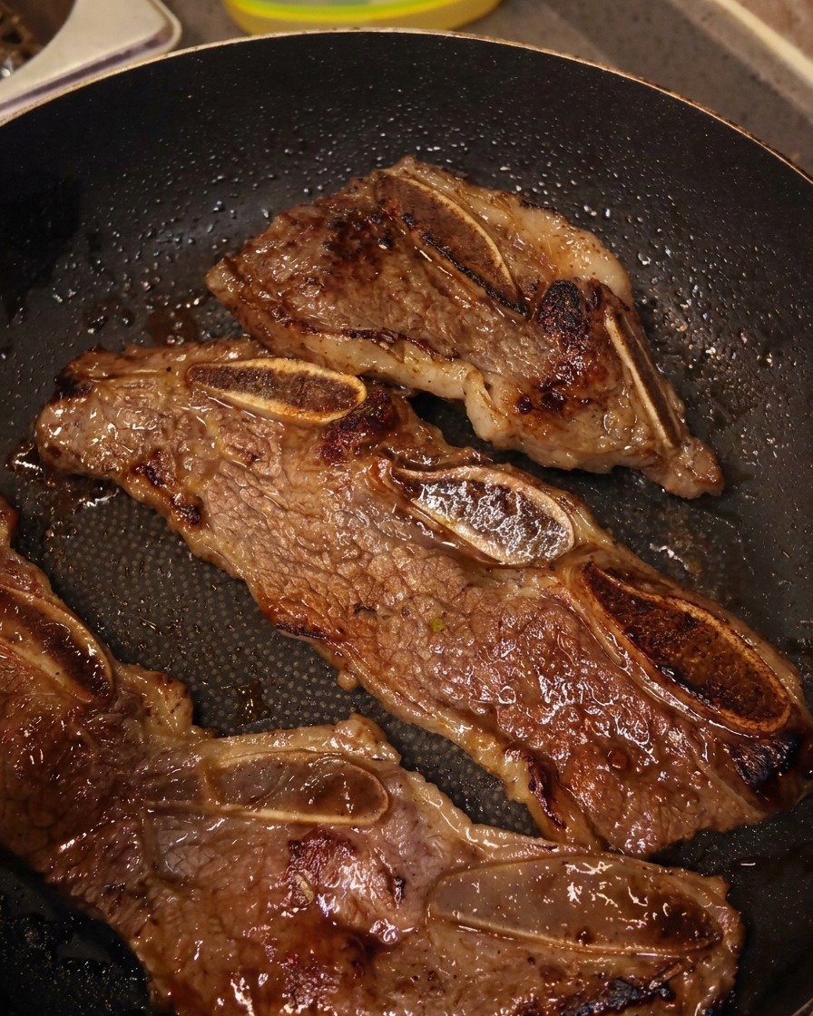 Forbici da cucina che tagliano strisce di costine di manzo in padella tra le ossa.