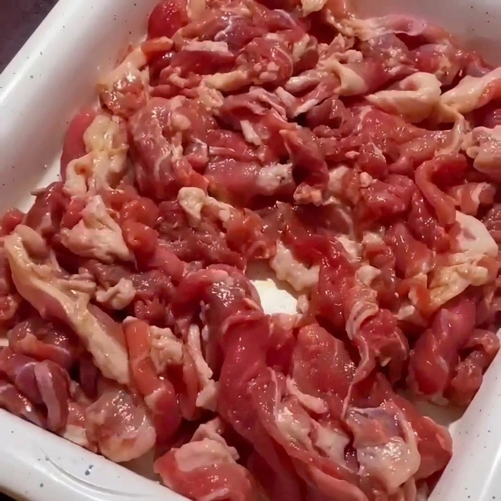 Primo piano di carne di maiale saltata in padella finché i bordi non sono dorati e la carne è quasi cotta.