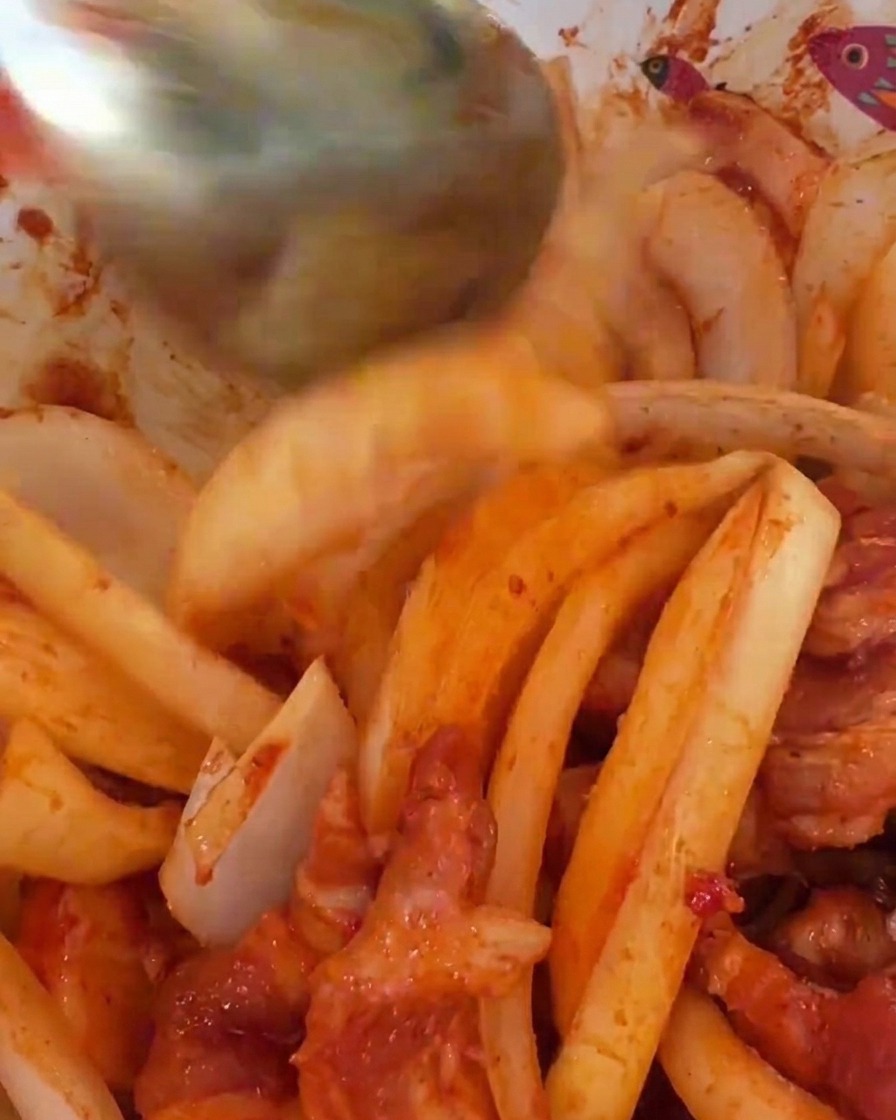 Grandi fette di cipolla bianca cruda unite alla carne di maiale marinata in rosso piccante.